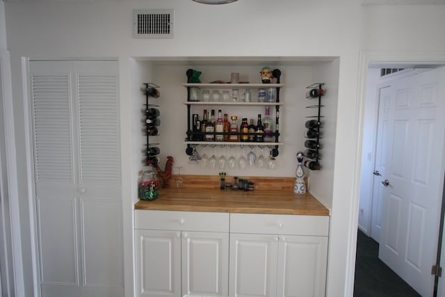 bar with carpet floors, butcher block countertops, and white cabinets