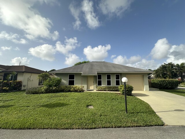 ranch-style house featuring a garage and a front lawn