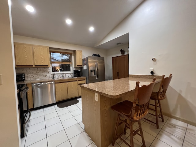 4634 Pine Grove Dr, Delray Beach, FL 33445 - kitchen featuring light tile patterned floors, a peninsula, appliances with stainless steel finishes, a sink, and decorative backsplash