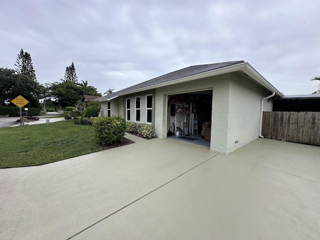4634 Pine Grove Dr, Delray Beach, FL 33445 - back of house featuring stucco siding, driveway, an attached garage, fence, and a lawn