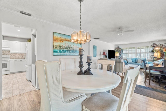 dining space featuring a textured ceiling, ornamental molding, ceiling fan with notable chandelier, and light wood-type flooring