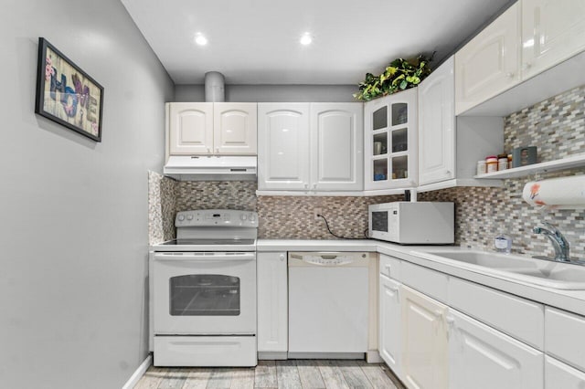 kitchen featuring tasteful backsplash, white appliances, sink, light hardwood / wood-style floors, and white cabinetry