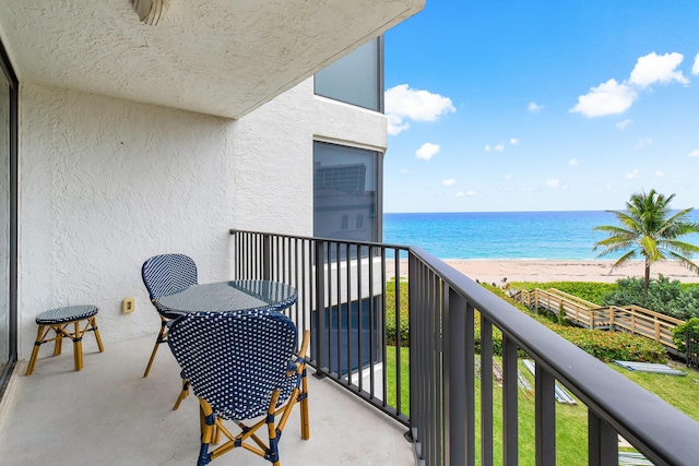 balcony featuring a view of the beach and a water view