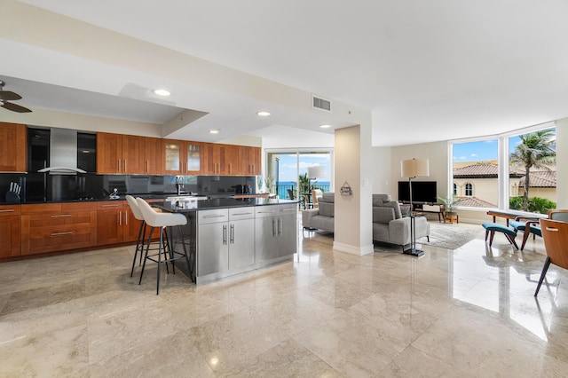 kitchen with a breakfast bar, tasteful backsplash, a healthy amount of sunlight, and wall chimney range hood