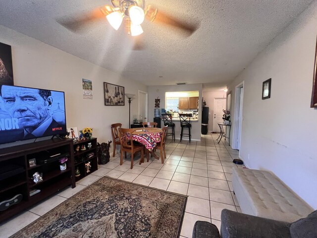 living room with a textured ceiling, light tile patterned floors, and ceiling fan