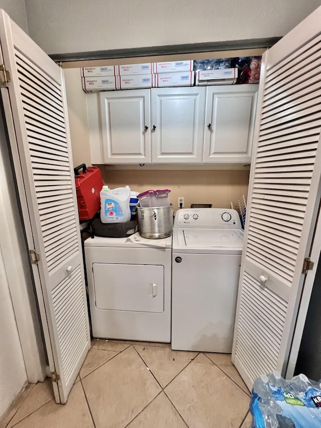 washroom with cabinets, washer and dryer, and light tile patterned floors