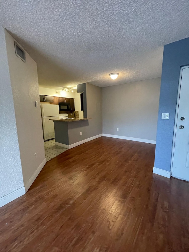 unfurnished living room with a textured ceiling and dark hardwood / wood-style floors