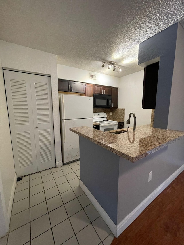 kitchen featuring white appliances, sink, kitchen peninsula, rail lighting, and a textured ceiling