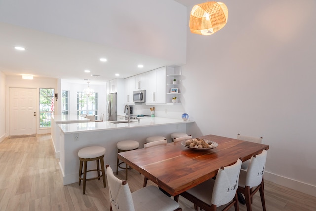 dining area with light hardwood / wood-style floors, sink, and an inviting chandelier