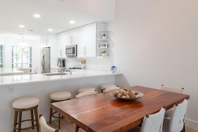 kitchen featuring sink, white cabinetry, hanging light fixtures, kitchen peninsula, and stainless steel appliances