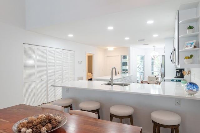 kitchen featuring a notable chandelier, stainless steel appliances, sink, a kitchen bar, and kitchen peninsula