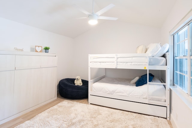 bedroom featuring light hardwood / wood-style floors, ceiling fan, and vaulted ceiling