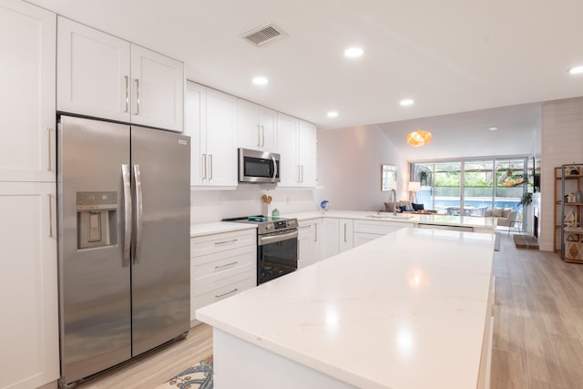 kitchen with white cabinetry, light wood-type flooring, kitchen peninsula, and stainless steel appliances