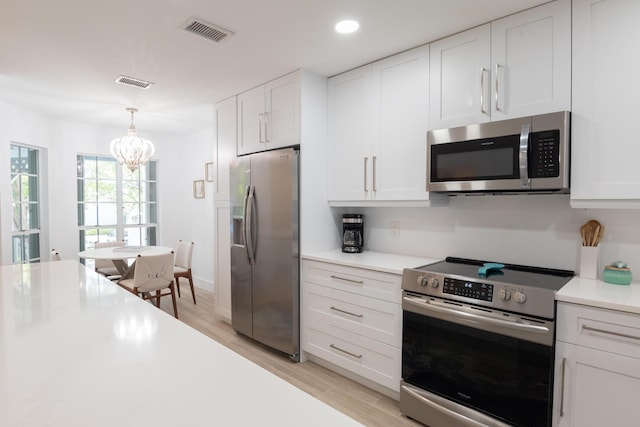 kitchen featuring hanging light fixtures, light hardwood / wood-style floors, white cabinets, and appliances with stainless steel finishes