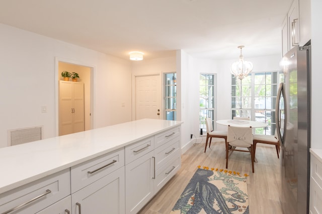 kitchen featuring stainless steel fridge, light hardwood / wood-style floors, decorative light fixtures, white cabinetry, and a notable chandelier