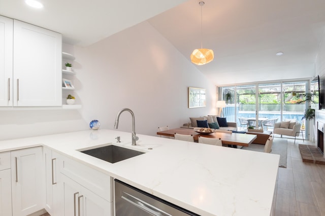 kitchen featuring white cabinetry, stainless steel dishwasher, light hardwood / wood-style floors, vaulted ceiling, and sink