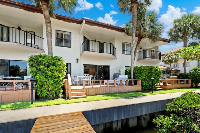 rear view of property featuring a balcony and a wooden deck