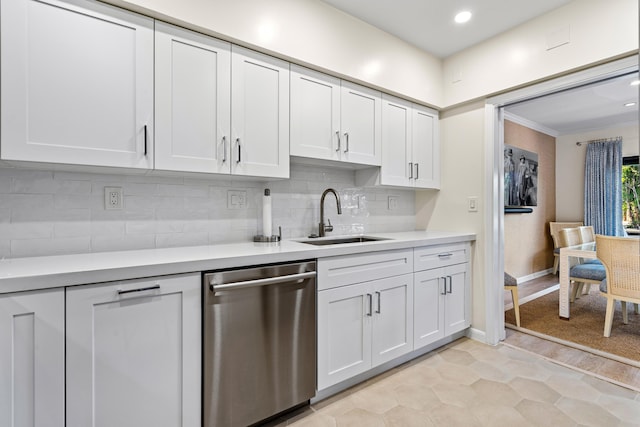 kitchen with light countertops, stainless steel dishwasher, white cabinetry, and a sink