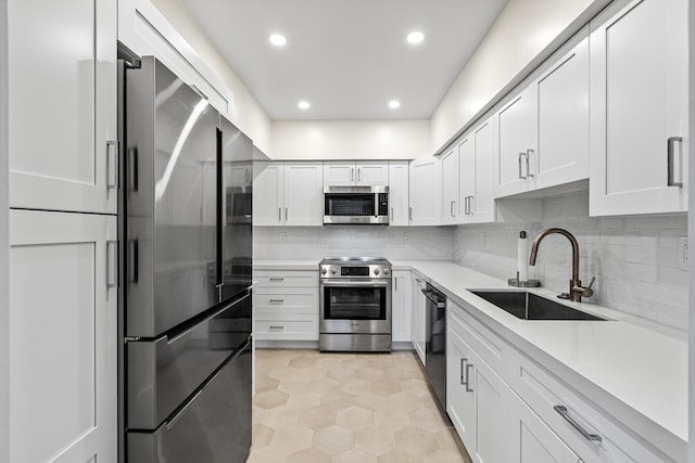 kitchen with stainless steel appliances, white cabinets, sink, backsplash, and light tile patterned flooring