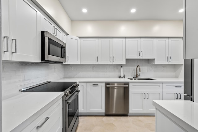 kitchen featuring white cabinetry, tasteful backsplash, light tile patterned floors, appliances with stainless steel finishes, and sink