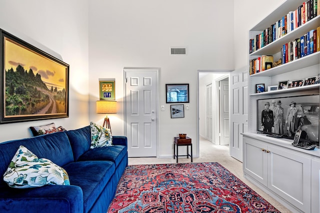 living area featuring visible vents, light carpet, and a high ceiling