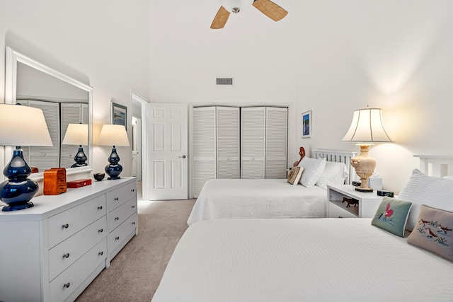 carpeted bedroom featuring a towering ceiling, a closet, and ceiling fan