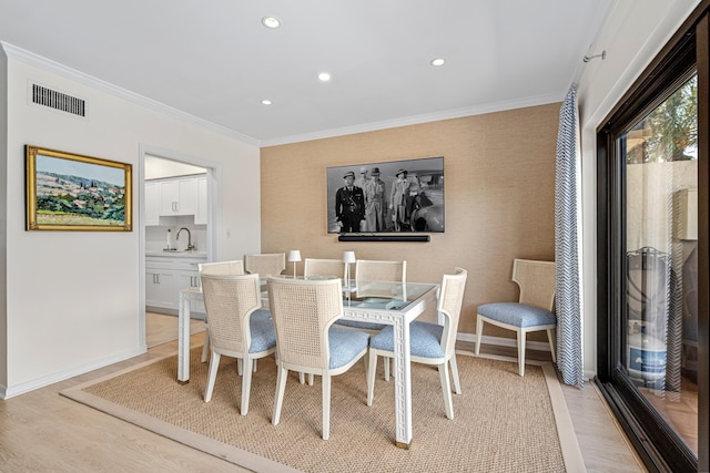 dining area featuring baseboards, light wood finished floors, ornamental molding, and visible vents