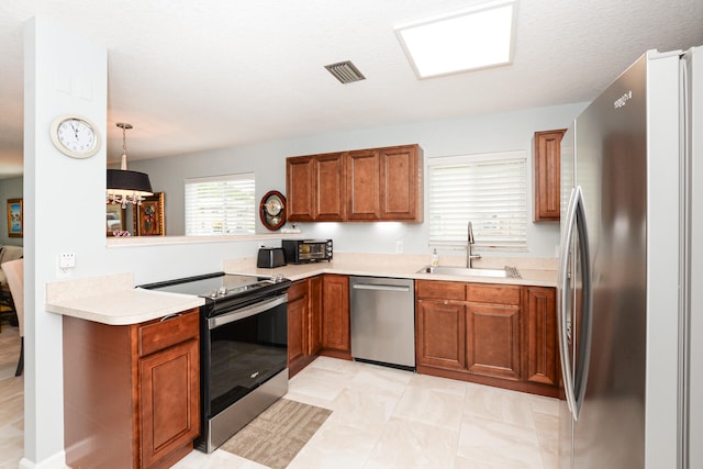 kitchen with sink, appliances with stainless steel finishes, hanging light fixtures, and light tile patterned floors