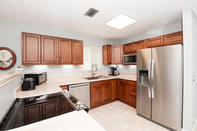 kitchen with stove, stainless steel fridge, sink, light tile patterned flooring, and dishwasher