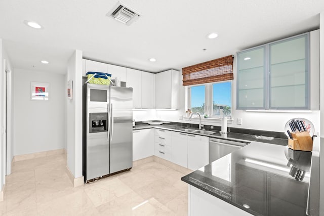 kitchen featuring dark stone counters, stainless steel appliances, white cabinets, sink, and light tile patterned flooring