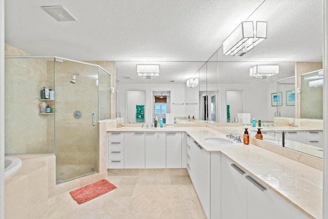 bathroom featuring dual vanity, plus walk in shower, tile patterned flooring, and a textured ceiling