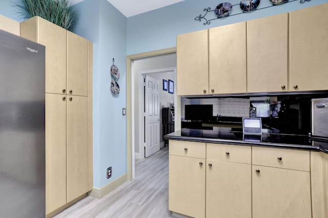 kitchen with decorative backsplash, light hardwood / wood-style floors, and light brown cabinetry