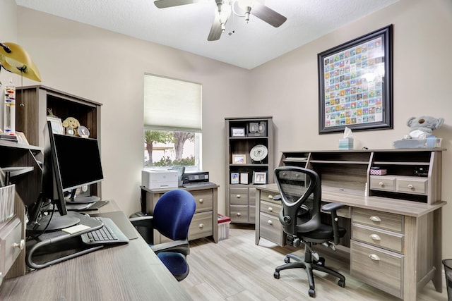 home office with a textured ceiling, ceiling fan, and light wood-type flooring