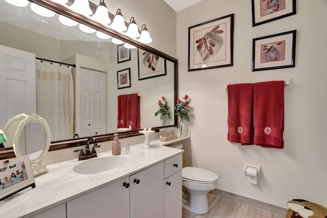 bathroom featuring wood-type flooring, toilet, and vanity