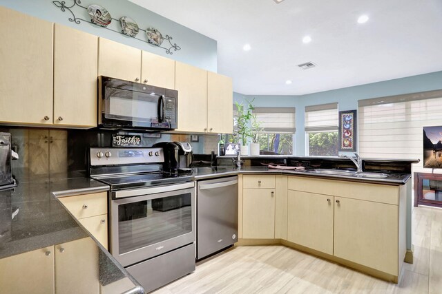 kitchen with cream cabinetry, sink, appliances with stainless steel finishes, and light wood-type flooring