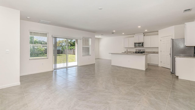 kitchen with white cabinets, sink, light stone countertops, an island with sink, and stainless steel appliances