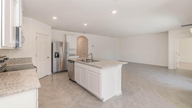 kitchen featuring a center island with sink, sink, light stone countertops, appliances with stainless steel finishes, and white cabinetry