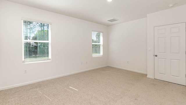 spare room with a wealth of natural light and light colored carpet