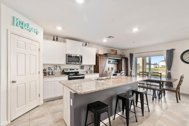 kitchen featuring white cabinetry, sink, a kitchen breakfast bar, an island with sink, and appliances with stainless steel finishes