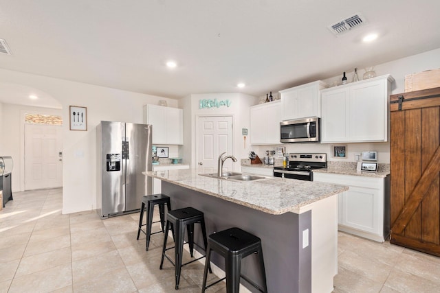 kitchen with sink, stainless steel appliances, a kitchen island with sink, a breakfast bar, and white cabinets