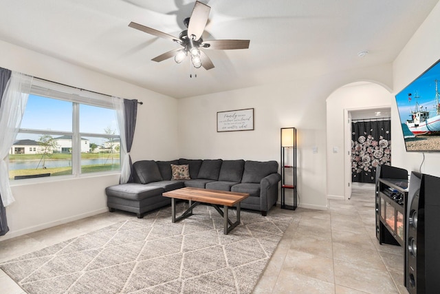 living room with a water view, ceiling fan, and light tile patterned flooring