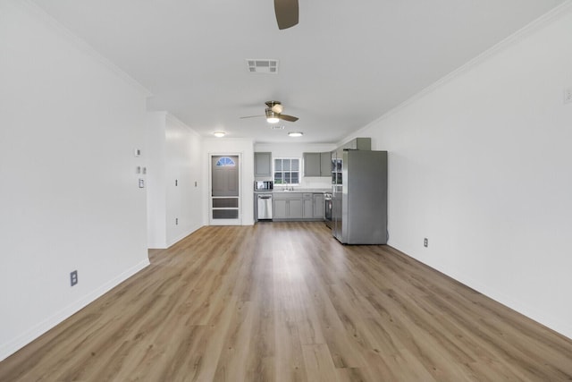 unfurnished living room featuring crown molding, sink, and light hardwood / wood-style floors