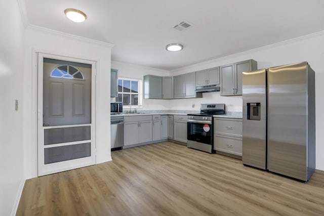 kitchen featuring ornamental molding, stainless steel appliances, light hardwood / wood-style flooring, and gray cabinetry