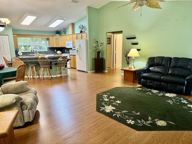 living room with light hardwood / wood-style floors, high vaulted ceiling, and ceiling fan