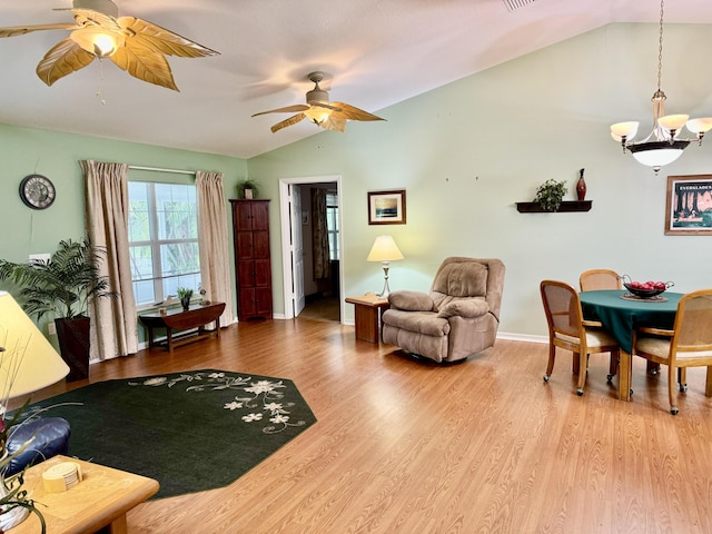 living room with ceiling fan with notable chandelier, vaulted ceiling, and hardwood / wood-style floors