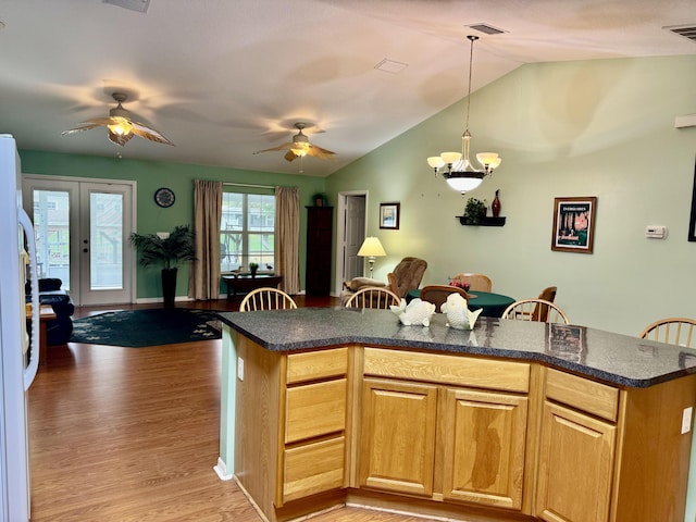 kitchen with white fridge, a kitchen bar, lofted ceiling, light wood-type flooring, and hanging light fixtures