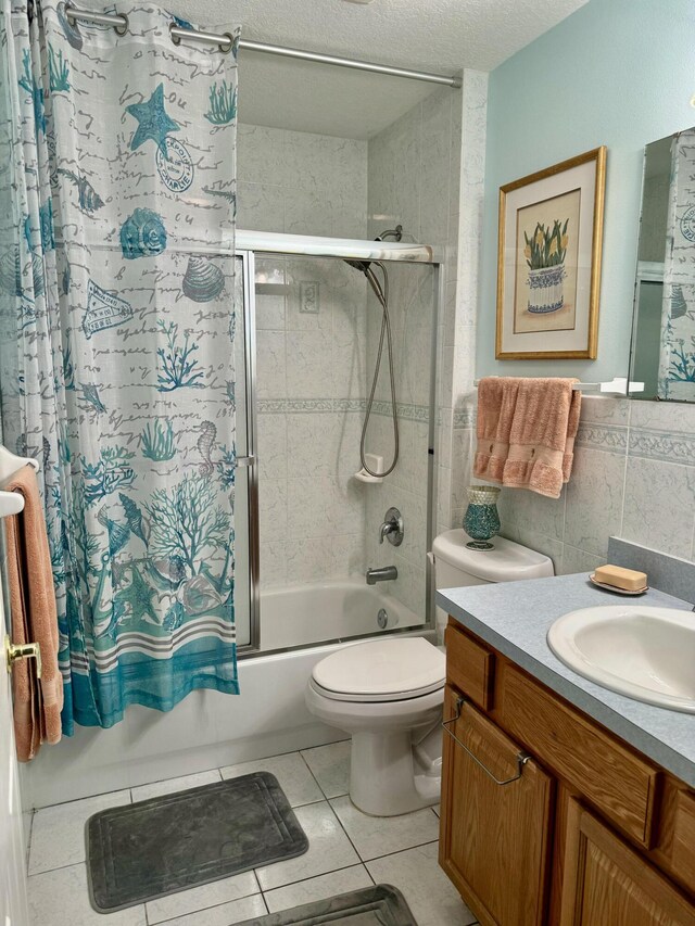 full bathroom with tile walls, vanity, toilet, tile patterned floors, and shower / bath combination with glass door