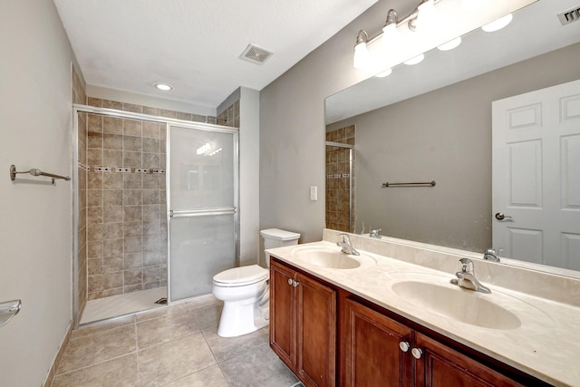 bathroom with a shower with shower door, tile patterned flooring, double sink vanity, and toilet