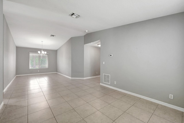 empty room with an inviting chandelier and light tile patterned floors