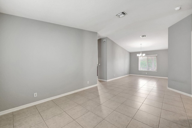 spare room with a notable chandelier and light tile patterned floors